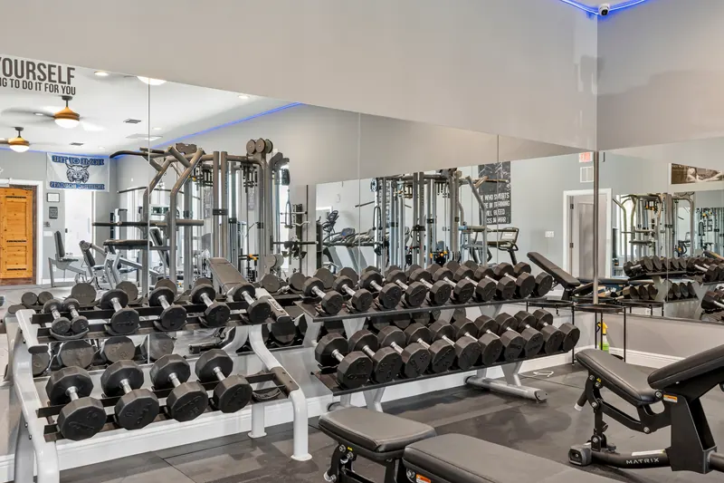 Two full dumbbell racks with adjustable benches in front of a mirrored wall.