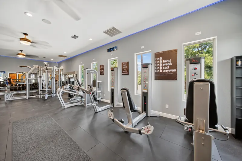 Weight-stack strength machines lined up along a wall of windows.